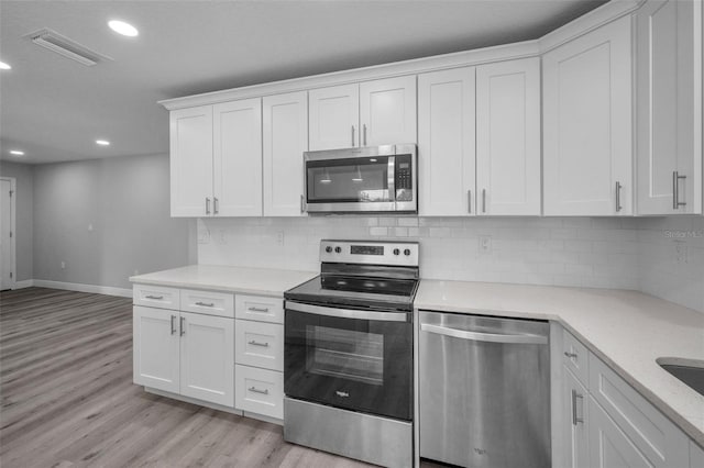 2307 N 47th St, Tampa, FL 33605 - kitchen with stainless steel appliances, baseboards, light wood finished floors, recessed lighting, and white cabinets