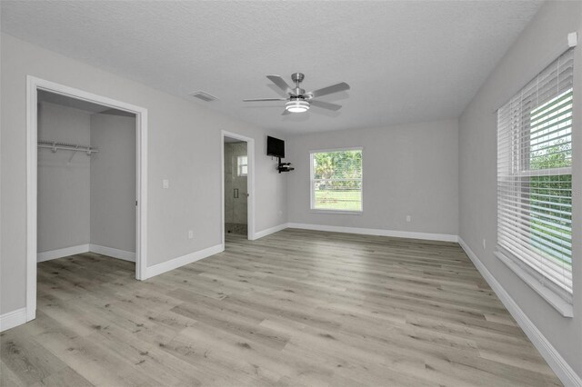 2307 N 47th St, Tampa, FL 33605 - unfurnished bedroom with light wood-style floors, baseboards, a spacious closet, a textured ceiling, and ceiling fan