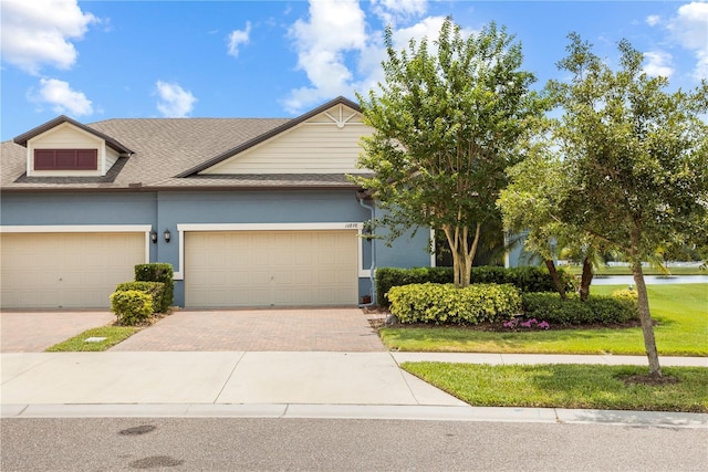 16898 Balance Cv, Land O Lakes, FL 34638 - view of front facade with decorative driveway, roof with shingles, a water view, stucco siding, and an attached garage