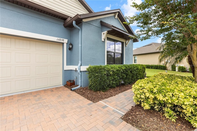 16898 Balance Cv, Land O Lakes, FL 34638 - entrance to property with stucco siding, an attached garage, and decorative driveway