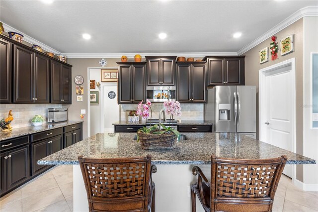 16898 Balance Cv, Land O Lakes, FL 34638 - kitchen featuring appliances with stainless steel finishes, decorative backsplash, crown molding, light tile patterned flooring, and dark stone countertops