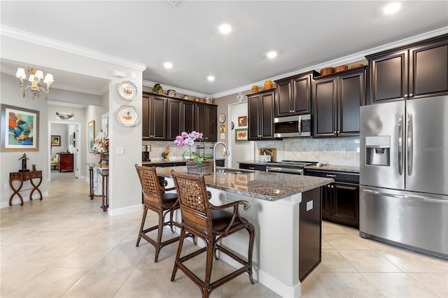 16898 Balance Cv, Land O Lakes, FL 34638 - kitchen with stainless steel appliances, a sink, crown molding, dark stone countertops, and light tile patterned floors