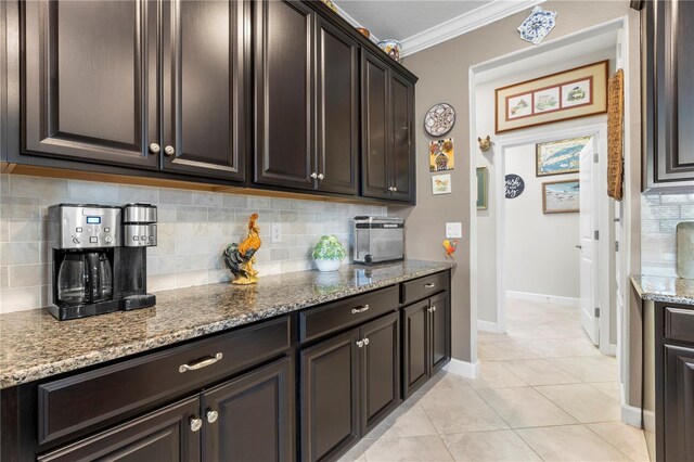 16898 Balance Cv, Land O Lakes, FL 34638 - kitchen with crown molding, tasteful backsplash, light stone counters, dark brown cabinets, and light tile patterned flooring
