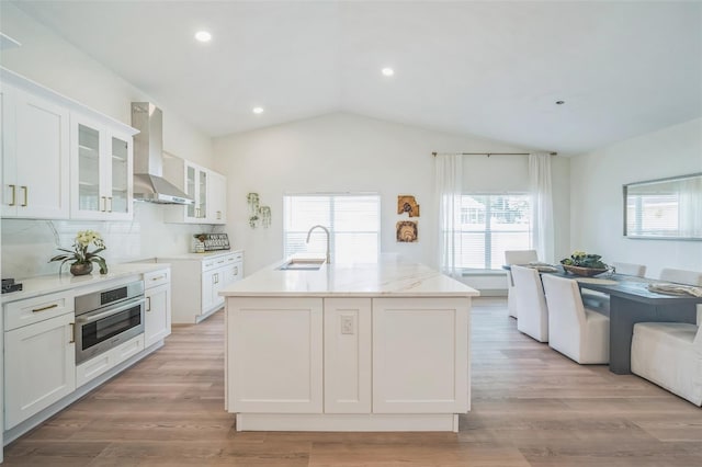 16106 Worlington Pl, Odessa, FL 33556 - kitchen with wall chimney exhaust hood, stainless steel oven, a sink, vaulted ceiling, and white cabinetry