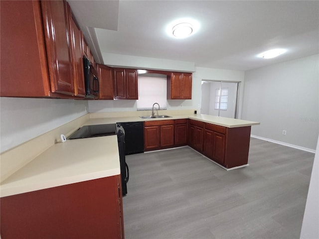 2045 Summit Dr, Dunedin, FL 34698 - kitchen with a sink, black appliances, a peninsula, light countertops, and light wood-type flooring