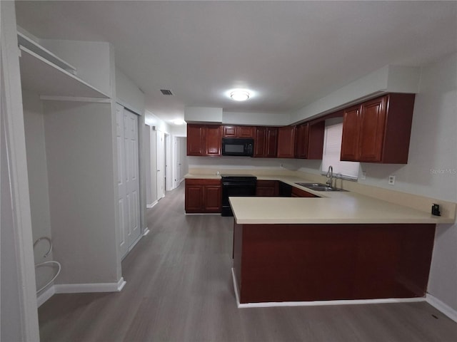 2045 Summit Dr, Dunedin, FL 34698 - kitchen with black appliances, a sink, baseboards, wood finished floors, and light countertops