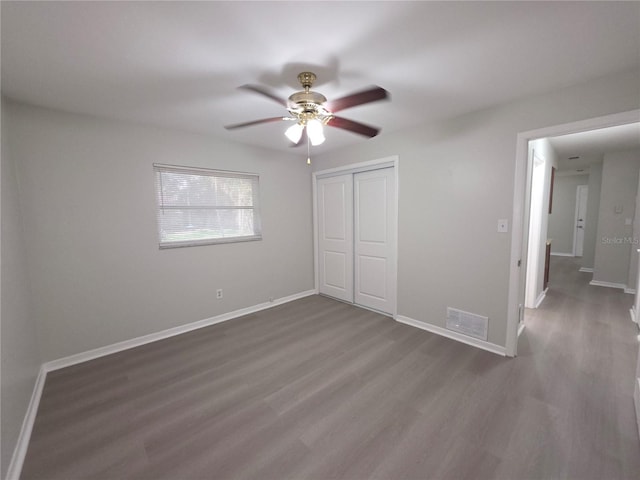 2045 Summit Dr, Dunedin, FL 34698 - unfurnished bedroom featuring wood finished floors, a closet, baseboards, and a ceiling fan