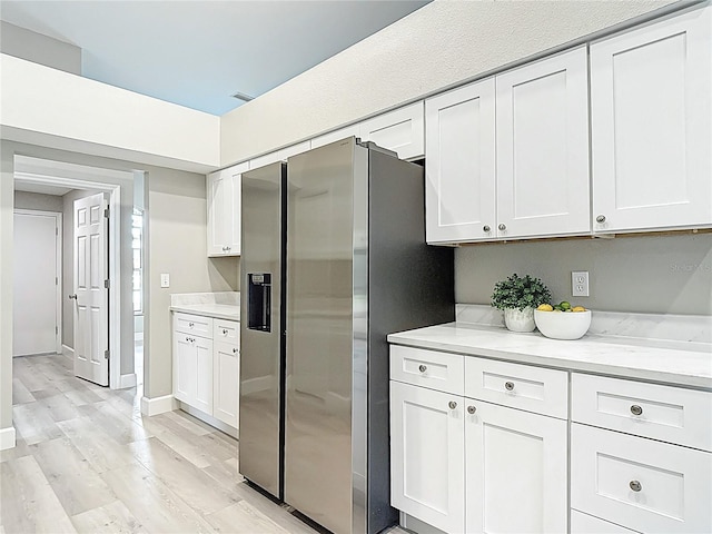5809 Silas Creek Ln, Wesley Chapel, FL 33545 - kitchen featuring stainless steel refrigerator with ice dispenser, white cabinetry, light wood-type flooring, and light stone counters