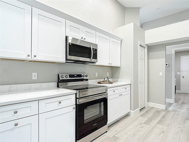5809 Silas Creek Ln, Wesley Chapel, FL 33545 - kitchen with appliances with stainless steel finishes, light wood-style floors, white cabinets, and light stone countertops