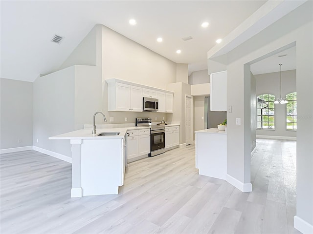 5809 Silas Creek Ln, Wesley Chapel, FL 33545 - kitchen featuring appliances with stainless steel finishes, a peninsula, light wood-style floors, high vaulted ceiling, and recessed lighting