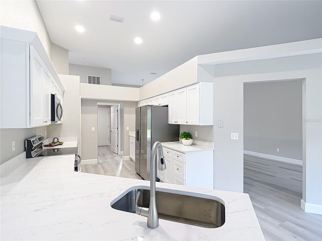 5809 Silas Creek Ln, Wesley Chapel, FL 33545 - kitchen with stainless steel appliances, white cabinets, light stone counters, and recessed lighting