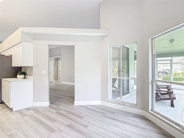5809 Silas Creek Ln, Wesley Chapel, FL 33545 - kitchen with light wood-style flooring, white cabinets, light countertops, and a high ceiling