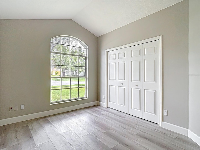 5809 Silas Creek Ln, Wesley Chapel, FL 33545 - unfurnished bedroom with light wood-style flooring, vaulted ceiling, and a closet
