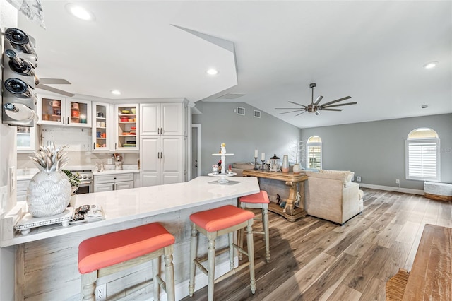 2812 SW 29th Ave, Cape Coral, FL 33914 - kitchen featuring ceiling fan, stainless steel stove, a breakfast bar, light countertops, and lofted ceiling