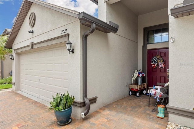 12026 Crestridge Loop, New Port Richey, FL 34655 - view of exterior entry with stucco siding, decorative driveway, and a garage