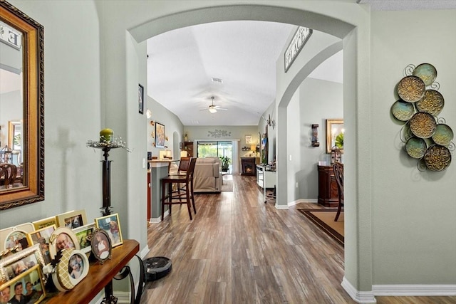 12026 Crestridge Loop, New Port Richey, FL 34655 - hallway featuring wood finished floors, arched walkways, baseboards, and lofted ceiling