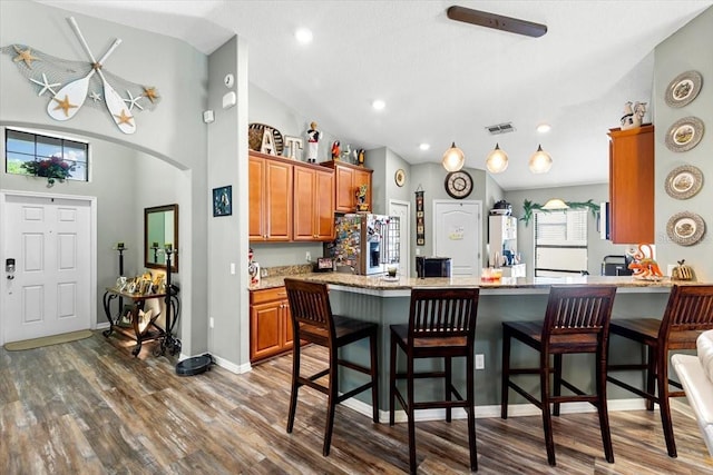 12026 Crestridge Loop, New Port Richey, FL 34655 - kitchen with stainless steel fridge with ice dispenser, lofted ceiling, dark wood-style flooring, brown cabinetry, and a kitchen breakfast bar