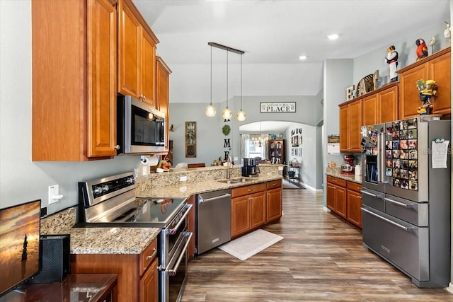 12026 Crestridge Loop, New Port Richey, FL 34655 - kitchen featuring stainless steel appliances, brown cabinetry, a peninsula, a sink, and dark wood-style flooring