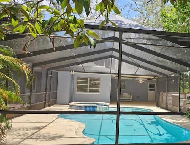 view of swimming pool with a patio, glass enclosure, a ceiling fan, and a pool with connected hot tub