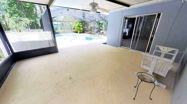 view of swimming pool featuring a ceiling fan, a pool with connected hot tub, a patio area, and glass enclosure