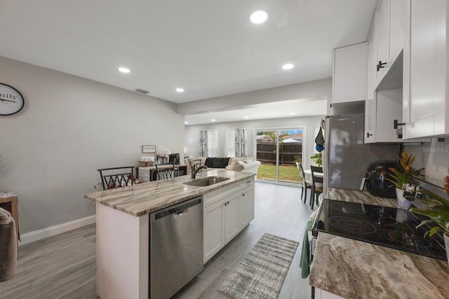 8339 75th Ave, Seminole, FL 33777 - kitchen featuring appliances with stainless steel finishes, light wood-style flooring, white cabinets, a sink, and a center island with sink