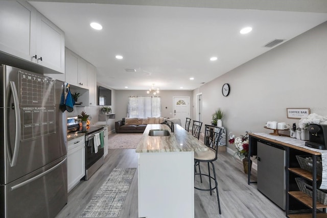 8339 75th Ave, Seminole, FL 33777 - kitchen featuring appliances with stainless steel finishes, a sink, light wood-style flooring, a breakfast bar, and recessed lighting
