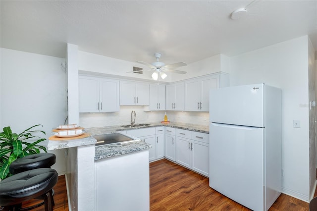 4154 56th St N Unit 720, Kenneth City, FL 33709 - kitchen with freestanding refrigerator, a sink, a peninsula, and white cabinetry