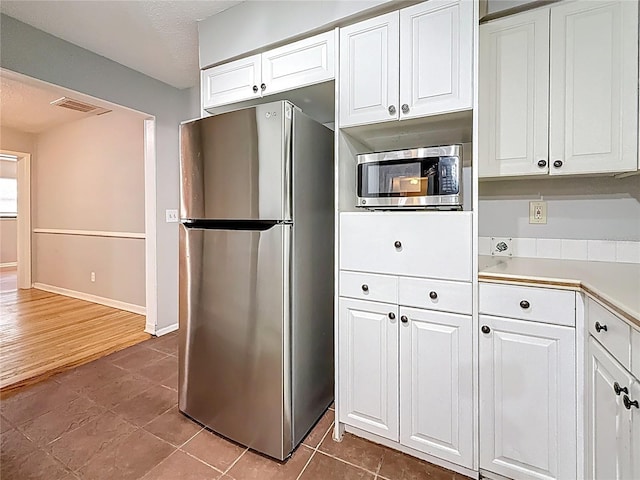1737 Prince Philip St, Clearwater, FL 33755 - kitchen with appliances with stainless steel finishes, white cabinets, light countertops, dark tile patterned floors, and a textured ceiling