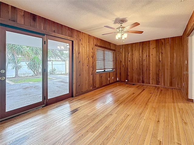 1737 Prince Philip St, Clearwater, FL 33755 - spare room with light wood-type flooring, wood walls, a textured ceiling, a ceiling fan, and baseboards