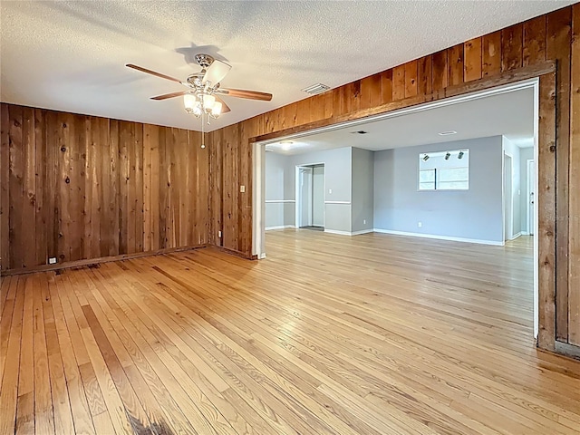1737 Prince Philip St, Clearwater, FL 33755 - empty room featuring light wood-style floors, wooden walls, a ceiling fan, baseboards, and a textured ceiling