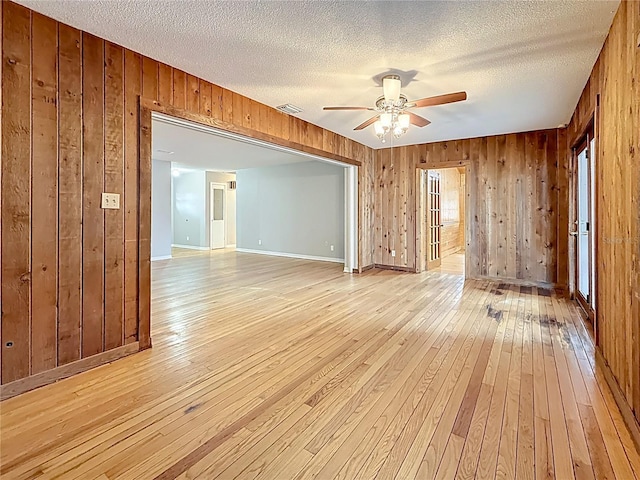 1737 Prince Philip St, Clearwater, FL 33755 - empty room with light wood-type flooring, a ceiling fan, wood walls, baseboards, and a textured ceiling