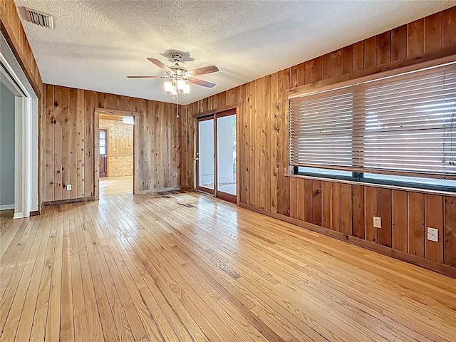 1737 Prince Philip St, Clearwater, FL 33755 - spare room featuring light wood finished floors, a ceiling fan, wood walls, a textured ceiling, and baseboards