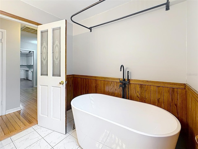 1737 Prince Philip St, Clearwater, FL 33755 - bathroom with a freestanding bath, a wainscoted wall, wood walls, and marble finish flooring