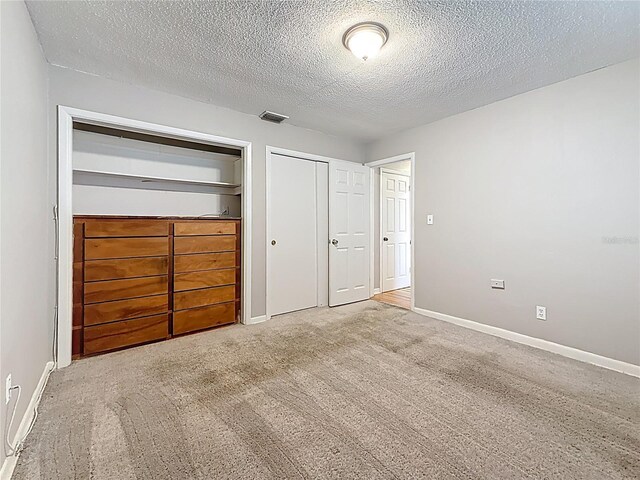 1737 Prince Philip St, Clearwater, FL 33755 - unfurnished bedroom featuring multiple closets, a textured ceiling, carpet, and baseboards