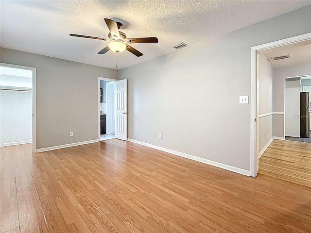 1737 Prince Philip St, Clearwater, FL 33755 - unfurnished bedroom with light wood finished floors, baseboards, a walk in closet, ceiling fan, and a textured ceiling