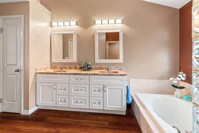 28390 Openfield Loop, Wesley Chapel, FL 33543 - full bathroom with double vanity, a garden tub, wood finished floors, and baseboards
