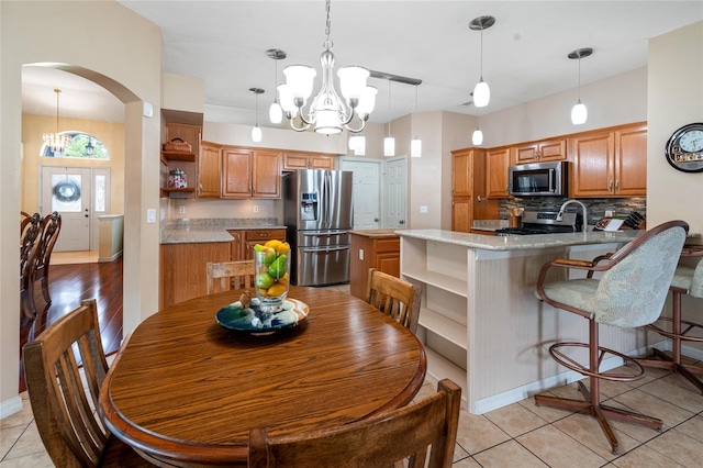 28390 Openfield Loop, Wesley Chapel, FL 33543 - dining space featuring a chandelier, arched walkways, baseboards, and light tile patterned floors