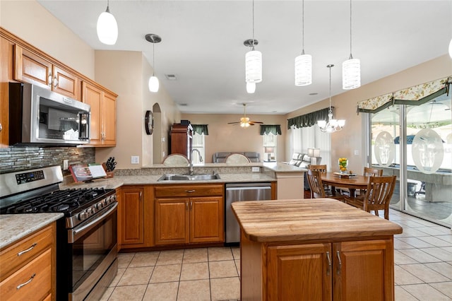 28390 Openfield Loop, Wesley Chapel, FL 33543 - kitchen featuring appliances with stainless steel finishes, a sink, a peninsula, open floor plan, and light tile patterned floors