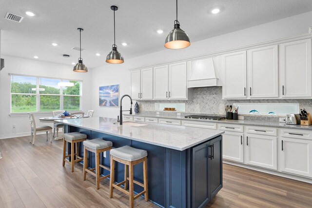 3559 Maple Bay Ln, Land O Lakes, FL 34638 - kitchen with custom range hood, decorative backsplash, white cabinets, wood finished floors, and recessed lighting