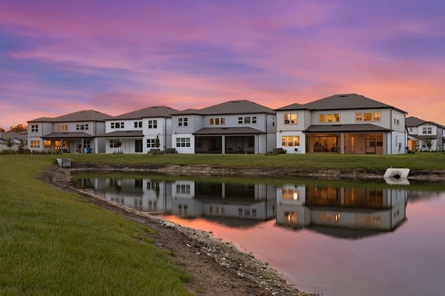3559 Maple Bay Ln, Land O Lakes, FL 34638 - back of house at dusk featuring a water view, a yard, and driveway