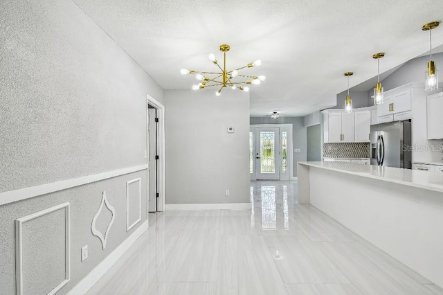 325 Gladstone Blvd, Englewood, FL 34223 - kitchen with stainless steel fridge, light countertops, white cabinetry, a chandelier, and decorative light fixtures