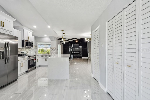 325 Gladstone Blvd, Englewood, FL 34223 - kitchen featuring appliances with stainless steel finishes, tasteful backsplash, white cabinetry, a kitchen island, and light countertops