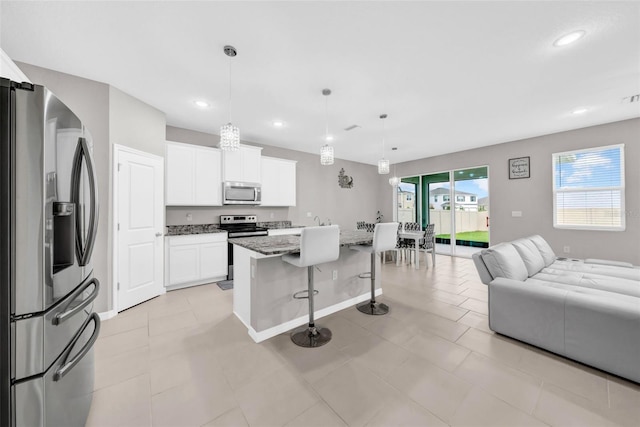 32136 Conchshell Sail St, Wesley Chapel, FL 33545 - kitchen with appliances with stainless steel finishes, open floor plan, a kitchen bar, a kitchen island, and white cabinets