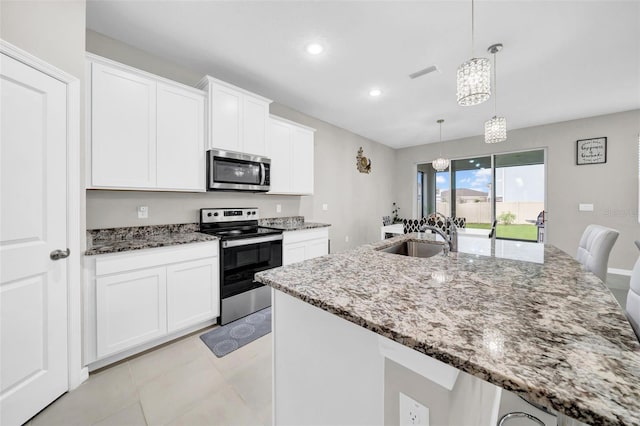 32136 Conchshell Sail St, Wesley Chapel, FL 33545 - kitchen with appliances with stainless steel finishes, a sink, light stone countertops, white cabinets, and a center island with sink