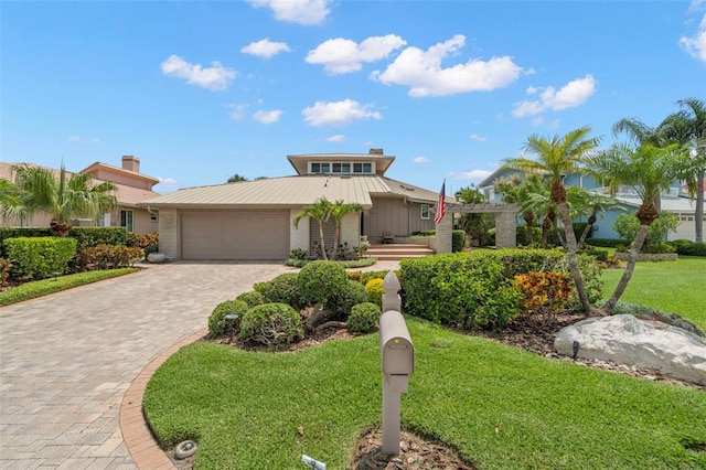 5782 Westshore Dr, New Port Richey, FL 34652 - mid-century home with an attached garage, decorative driveway, a front yard, metal roof, and brick siding