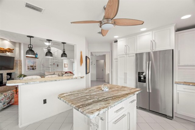 5782 Westshore Dr, New Port Richey, FL 34652 - kitchen with stainless steel fridge, ceiling fan, light tile patterned floors, light stone counters, and white cabinets