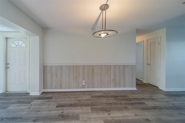 10005 41st St N, Pinellas Park, FL 33782 - unfurnished dining area featuring dark wood-style floors, a wainscoted wall, baseboards, a textured ceiling, and wooden walls