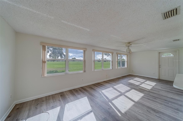 10005 41st St N, Pinellas Park, FL 33782 - empty room featuring plenty of natural light, wood finished floors, ceiling fan, a textured ceiling, and baseboards