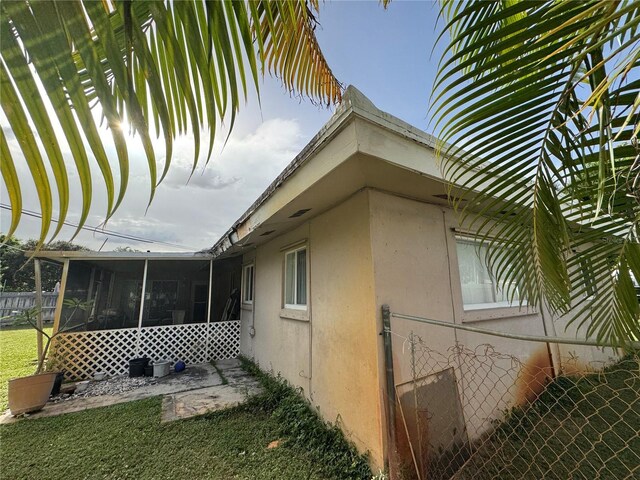 2160 NE 53rd St, Fort Lauderdale, FL 33308 - view of side of home with a sunroom, stucco siding, and a lawn