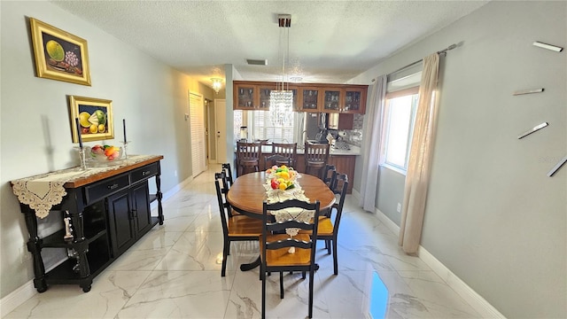 6424 Thicket Trl, New Port Richey, FL 34653 - dining room with light marble finish flooring, a textured ceiling, and baseboards